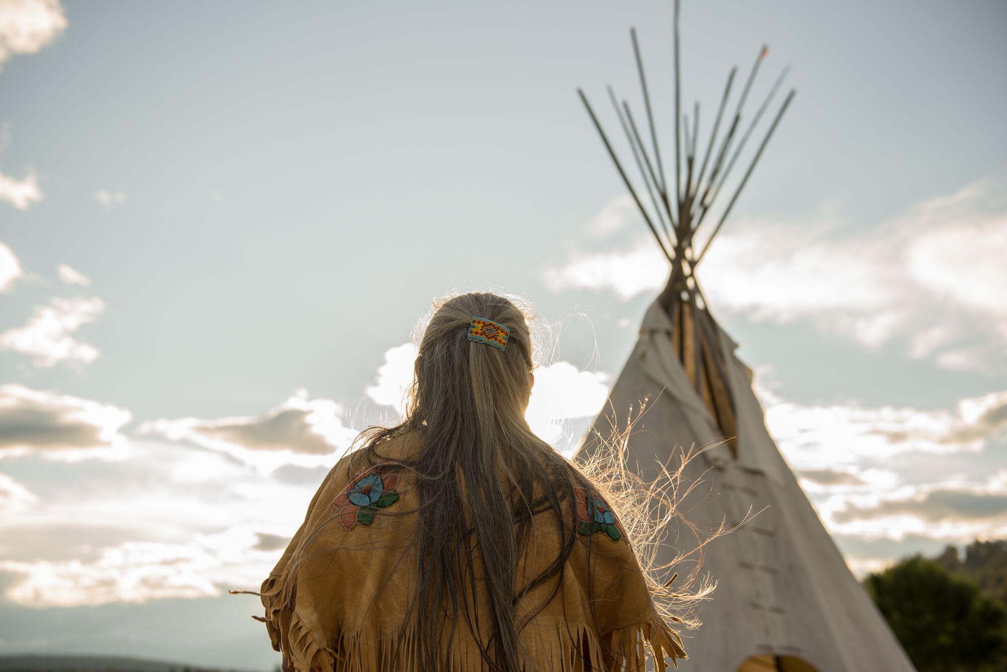 Ktunaxa elder in regalia next to a teepee at St Eugene Golf Resort